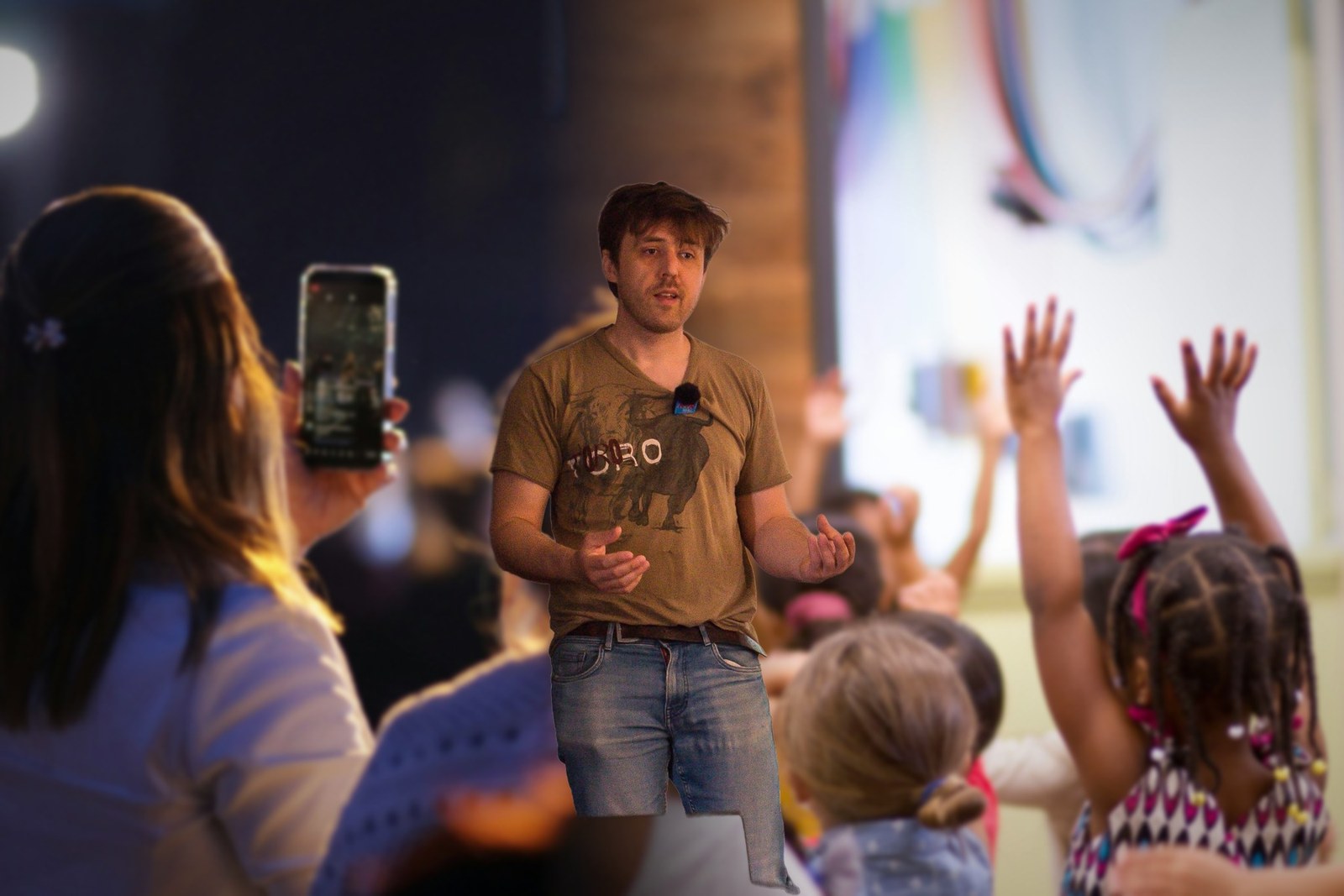 Antonin Atger devant un public qui filme avec un téléphone et des enfants qui lèvent la main