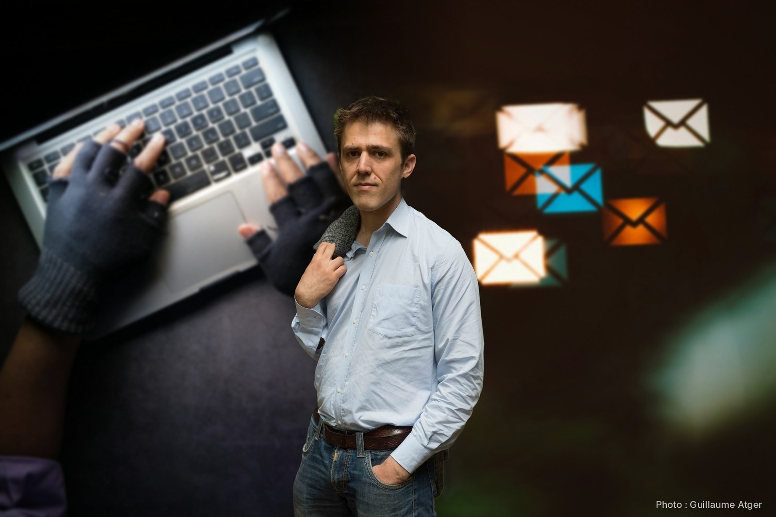 Antonin Atger devant des mains gantées sur un clavier et des enveloppes de mails lumineuses