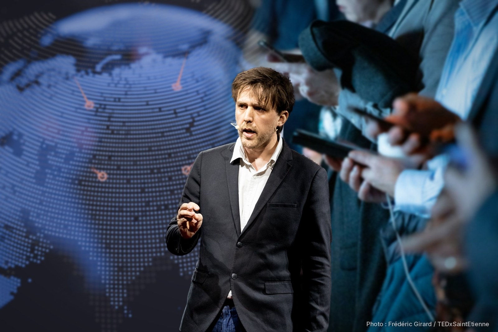 Antonin Atger sur la scène du TEDx, devant un globe numérique et une rangée de personnes rivées à leur téléphone