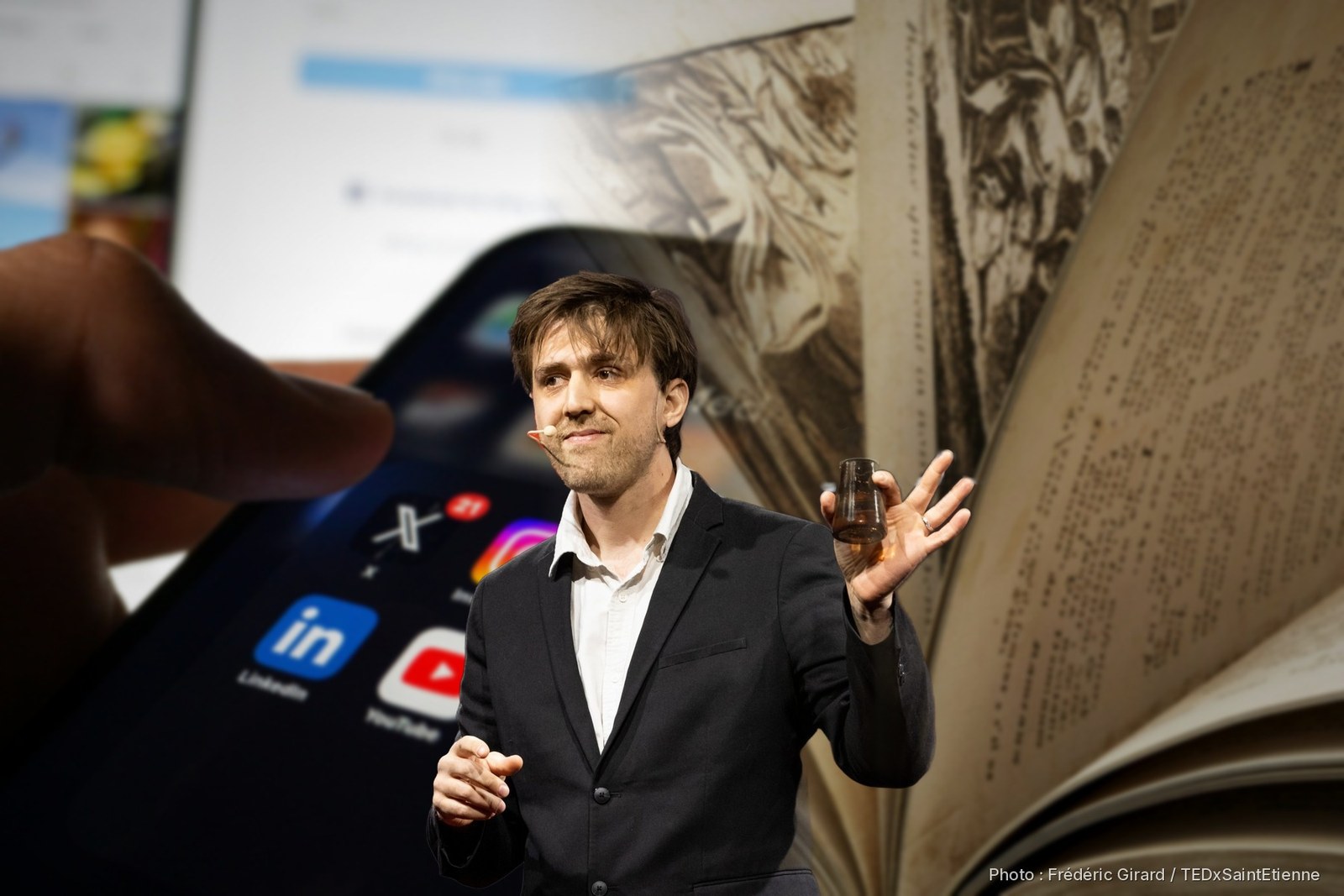 Antonin Atger sur la scène du TEDx, devant un smartphone et un livre ancien