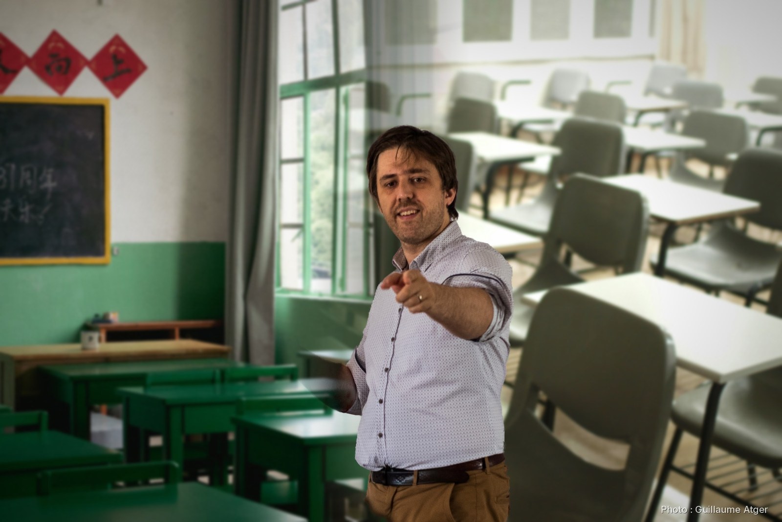 Antonin Atger, le bras tendu, devant des salles de classe vides