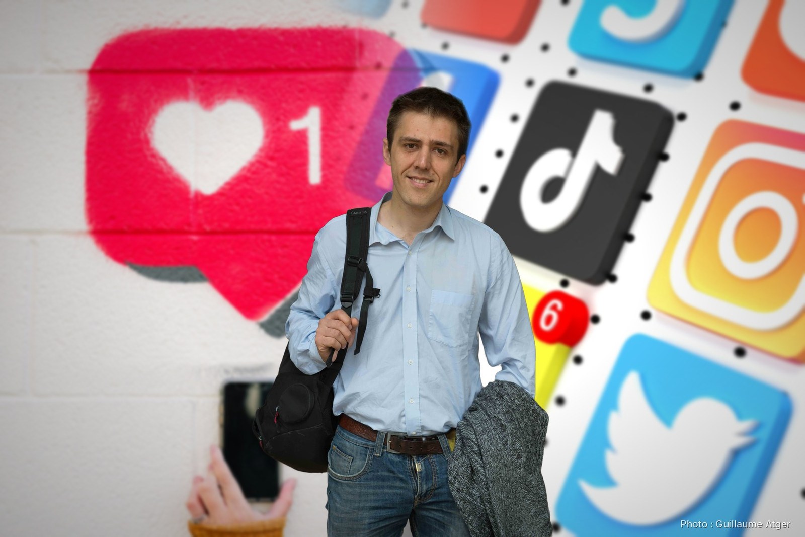Antonin Atger devant un mur peint d'un « j'aime » et des icônes de réseaux sociaux
